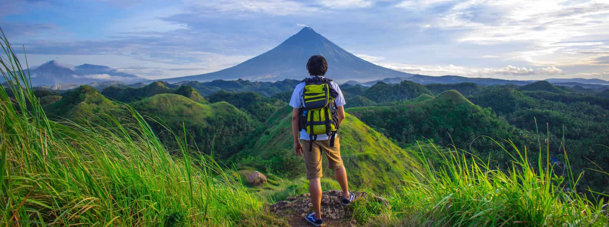 A lone solo traveler posing near a mountain while traveling abroad